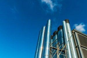 Large building and industrial plant chimneys against a clear blue sky Large building and industrial plant chimneys against a clear blue sky